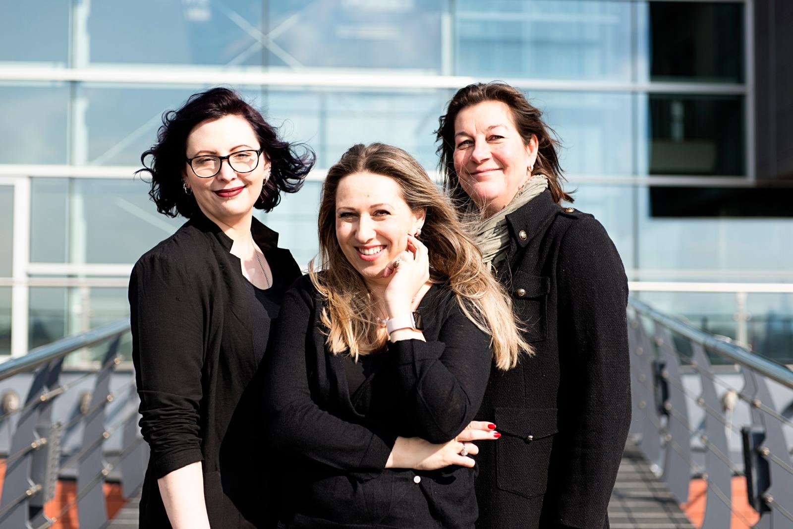 Drie FacilityBee-medewerksters glimlachend buiten een modern kantoorpand